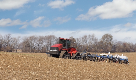 Red tractor pulling anhydrous ammonia tanks in a farm field