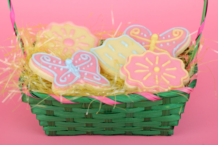 Easter sugar cookies in a green basket on a pink background