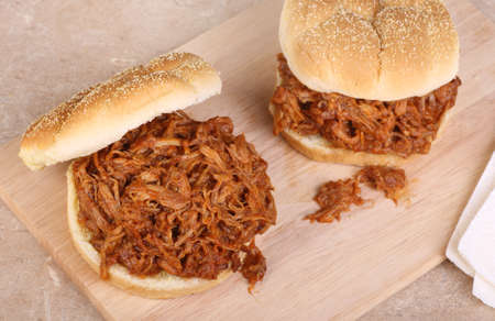 Two pulled pork barbecue sandwiches on a cutting board