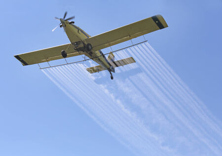 Airplane spraying insecticides over a farm field