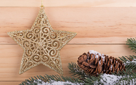 Gold holiday star with pine cone and needles on a wooden backgroundの写真素材
