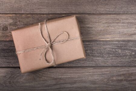 Single brown package tied with string on a wood backgroundの写真素材
