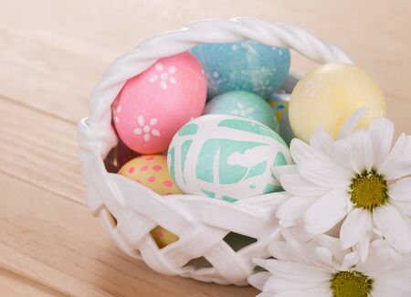 Decorated Easter eggs in a white basketの写真素材