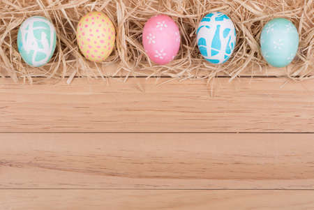 Border of Easter eggs and raffia on wood backgroundの写真素材