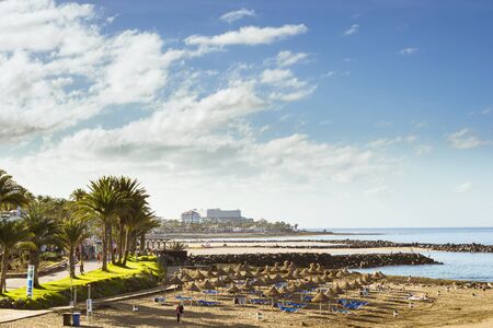 TENERIFE, SPAIN - JANUARY 14, 2013: Straw umbrellas and loungers on the beach Costa Adeje, Tenerife, Canary Islands, Spainのeditorial素材