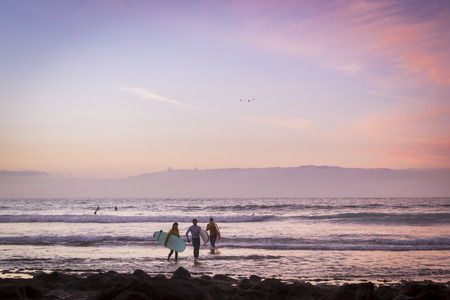 TENERIFE, SPAIN - JANUARY 14, 2013: Surfers surf on the waves, bright sunset on the coast in the popular canarian resort Playa de Las Americas, Tenerife, Canary Islands, Spainのeditorial素材