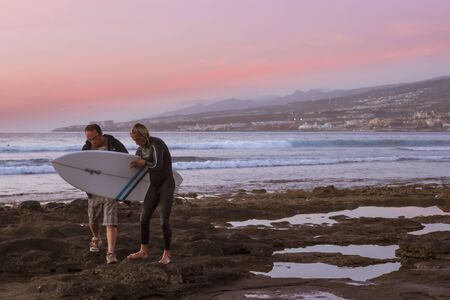 TENERIFE, SPAIN - JANUARY 14, 2013: Surfers surf on the waves, bright sunset on the coast in the...