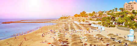 TENERIFE, SPAIN - JANUARY 14, 2013: Sandy beach with thatched parasols and sunbeds, Costa Adeje, Tenerife, Canary Islands, Spainのeditorial素材