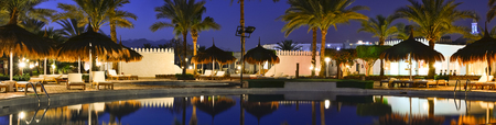 SHARM EL SHEIKH, EGYPT - FEBRUARY 27, 2014: February night on the beach, straw umbrellas and sunbeds by the pool at the hotel beach Albatros resort, Sharm El Sheikh, Egyptのeditorial素材
