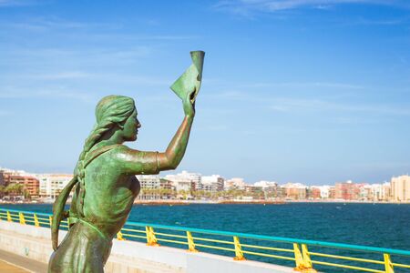 Bronze monument of woman with letter in hand, which accompanies sailor.の写真素材