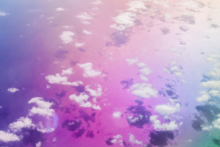 Clouds over Crete sea, ripples from the waves on water, aerial view from flight altitude of aircraft. Sun reflected from the water surface through the clouds. Front blurred background with bokeh. Greeceの写真素材