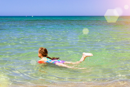Cute happy girl child relaxing and bathed on the shores of Cretan sea in rescue arm cover. Sunny sandy Livadi beach in sea Bay of resort village Bali, Rethymno, Crete, Greeceの写真素材