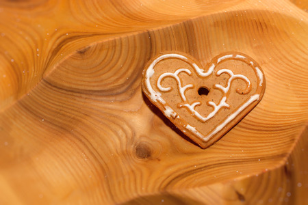 Cookies in shape of heart for Valentine's Day on wooden tray. Festive treat for celebrating lovers. Holiday gingerbread with icing on wooden textureの写真素材