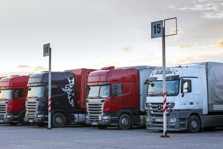 Narva, Estonia - August 20, 2016: Scania & Mercedes heavy trucks loaded with goods trailers, parked in waiting area on Estonian-Russian state border crossing. International hard transportation and logistics. Transport infrastructure in evening at sunsetのeditorial素材