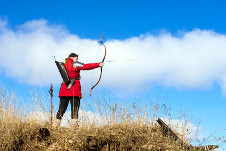 Saint-Petersburg, Russia - March 13, 2016: Archer in traditional costume shoots an arrow at target. National sports entertainment outdoors. Hit target as success of business and Affairs. Funny Nicholas Fortressのeditorial素材