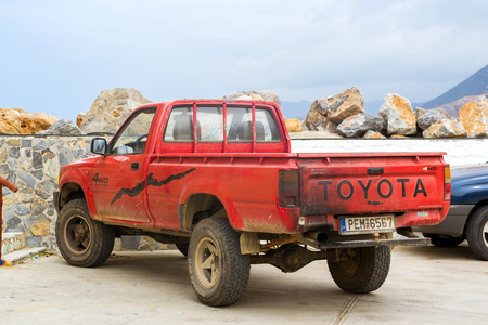 Bali, Greece - April 30, 2016: Old red pickup truck Toyota parked on Mithos beach promenade in sea...
