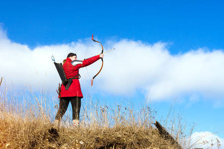 Saint-Petersburg, Russia - March 13, 2016: Archer in traditional costume shoots an arrow at target. National sports entertainment outdoors. Hit target as success of business and Affairs. Funny Nicholas Fortressのeditorial素材