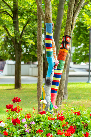 Vilnius, Lithuania - August 8, 2012: Maple tree in Vincas Kudirka square with trunk knitted around mixed spinning cloth. Street art in city Park in centre of Vilnius. Creative knitwear for treesの写真素材
