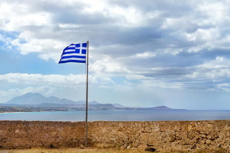 Greek flag flies on flagpole on tower of castle Fortezza - Venetian fortress on hill Paleokastro in...