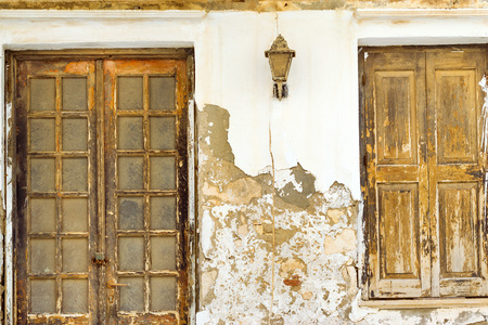 Old concrete wall with two dusty wooden doors. Resort classic Greek architecture in port city...