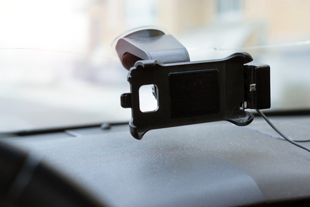 Car smartphone holder attached to the windscreen of automobile. Accessories for vehicles, for ease of control a car in the way. Phone holder with charging functionの写真素材