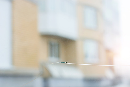 Broken car glass with crack on windshield of auto. Blurred grey backdrop of transport road in backgroundの写真素材
