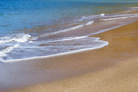 Surf and tide of foamy waves on a sandy beach. Sunny sandy Livadi beach in sea Bay of resort village Bali. Sea waves wash the sandy deserted beach. Bali, Rethymno, Crete, Greeceの写真素材