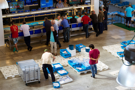 Blanes, Spain - 31 may, 2018: Buyers are traded at conveyor. Fish auction for wholesalers and restaurants. Blue plastic containers with catch of sea fish, ocean delicacies. Industrial catch of fishのeditorial素材