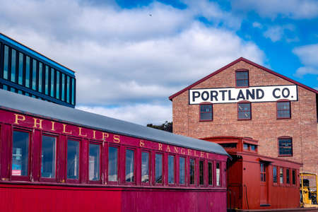Portland, Maine - U.S.A. - 10-28-2021: A red train sits i front of the old Portland Co building in...