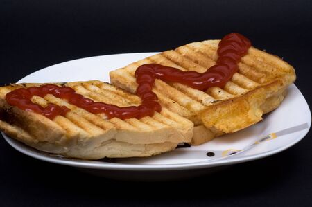 Tosts with cheese and ketchup on black background being based on plate.の写真素材