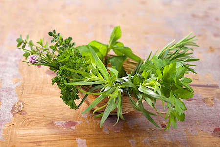 Little basket of  aromatic herbs  on old wooden plank backgroundの写真素材