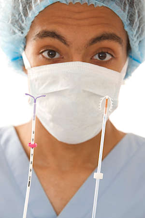 Young doctor holding two type of  IUD birth control copper coil device in hand, used for...