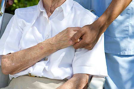 Symbol of comfort and support from care giver to elderly woman outdoor holding her hand