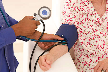 Doctor taking blood pressure to patient at home 