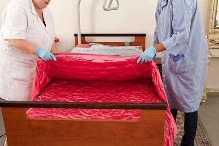 home-care woman making bed and changing bedding at elderly  homeの写真素材