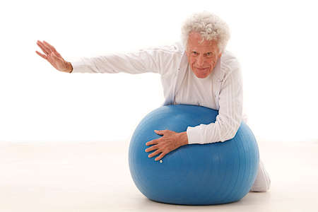 Active elderly man  exercising with fitness ball in gym  isolated on white backgroundの写真素材