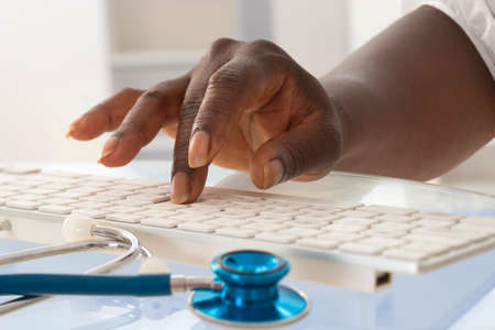 African female doctor taping on his keyboardの写真素材