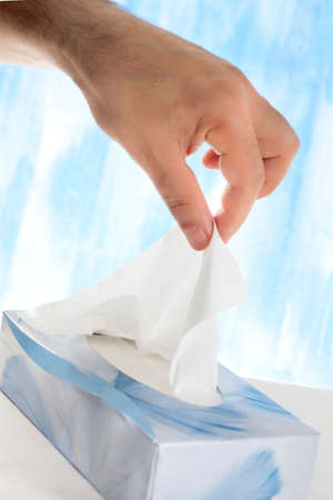 A hand pulls a tissue from a tissue box.の写真素材