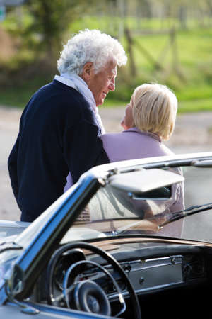 Mature couple in countryside by car, smiling, portrait