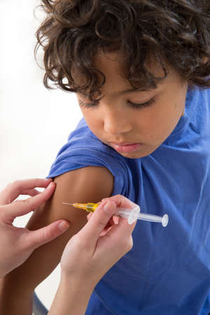 little boy looking at his arm, while receiving vaccineの写真素材