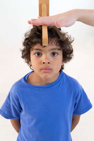 Doctor measures growth smiling boy in medical office, focus on the boyの写真素材