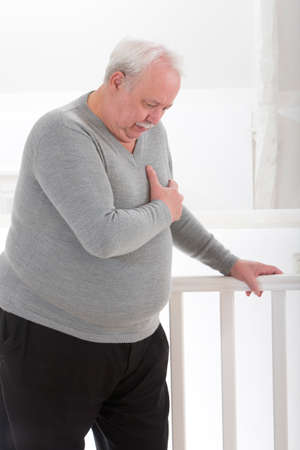 oerweight senior man' hand grabbing his  chest