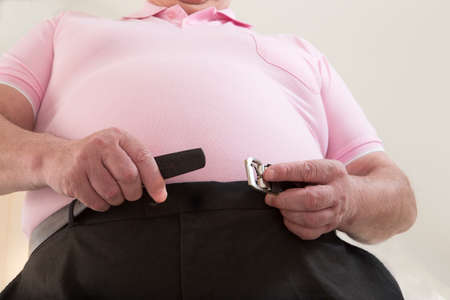 overweight senior man in difficulty to close His trousersの写真素材