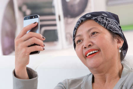 Smiling senior asian thai woman using cell phone