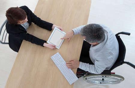 Businessman in wheelchair With His personal assistant in the office