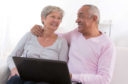 Senior couple looking information at home with computer.の写真素材