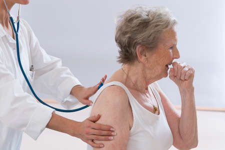 Senior woman coughing while doctor examining herの写真素材
