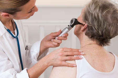 doctor examining elderly patient's earsの写真素材