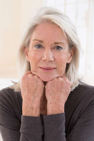 portrait of pretty senior woman with hands on her face