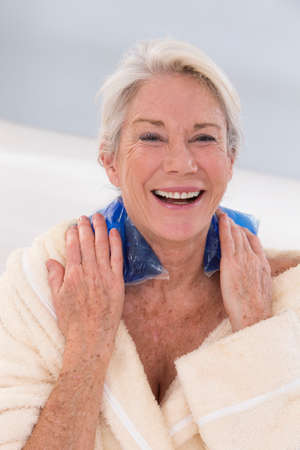 Senior woman putting gel pack on neckの写真素材